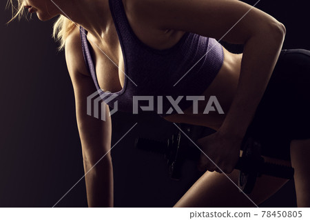 Slim athletic woman Holding dumbbell in the hand on black Slim athletic woman Holding dumbbell in the hand on black 78450805