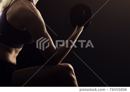 Slim athletic woman Holding dumbbell in the hand on black Slim athletic woman Holding dumbbell in the hand on black 78450806