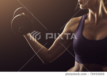Slim athletic woman Holding dumbbell in the hand on black Slim athletic woman Holding dumbbell in the hand on black 78450808