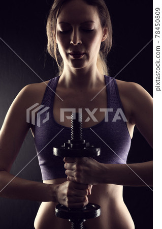 Slim athletic woman Holding dumbbell in the hand on black Slim athletic woman Holding dumbbell in the hand on black 78450809