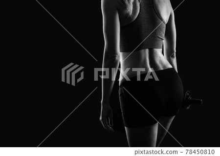 Slim athletic woman Holding dumbbell in the hand on black Slim athletic woman Holding dumbbell in the hand on black 78450810