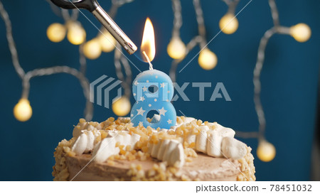 Birthday cake with 8 number candle on blue backgraund set on fire by lighter. Close-up Birthday cake with 8 number candle on blue backgraund set on fire by lighter. Close-up 78451032