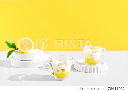 Lemon mousse or ice cream in a glass cups on yellow background. Traditional Italian recipe of lemon tiramisu or granita. Delicious summer dessert. Lemon mousse or ice cream in a glass cups on yellow background. Traditional Italian recipe of lemon tiramisu or granita. Delicious summer dessert. 78451912