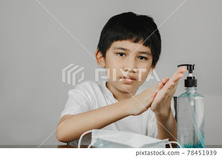 Closeup a boy face cleaning his hands with alcohol gel Closeup a boy face cleaning his hands with alcohol gel 78451939