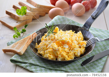 Scrambled eggs served in an iron frying pan 78452138