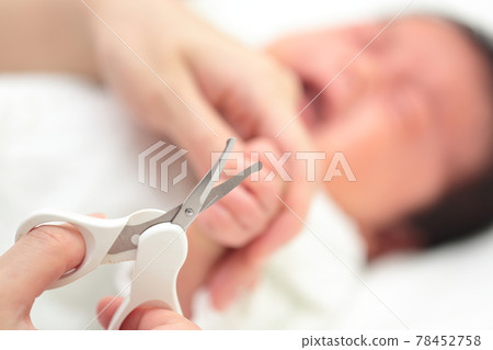 Mom cutting the nails of a newborn baby's hand Mom cutting the nails of a newborn baby's hand 78452758