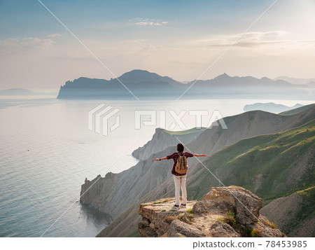 A young Asian woman with a backpack hiking in the summer. A young Asian woman with a backpack hiking in the summer. 78453985