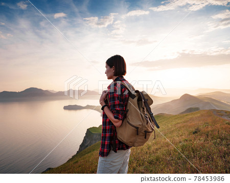 A young Asian woman with a backpack hiking in the summer. A young Asian woman with a backpack hiking in the summer. 78453986
