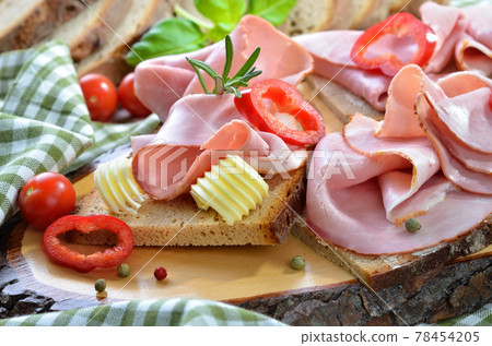 Snack with smoked ham and fresh farm-baked bread, served on a wooden cut Snack with smoked ham and fresh farm-baked bread, served on a wooden cut 78454205