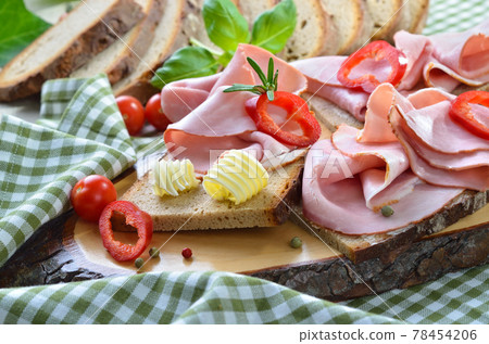 Snack with smoked ham and fresh farm-baked bread, served on a wooden cut Snack with smoked ham and fresh farm-baked bread, served on a wooden cut 78454206