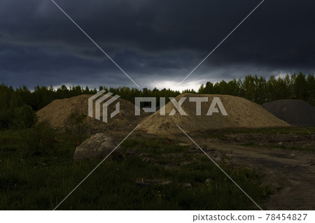 Heaps of sand at a construction site on city outskirts under storm clouds Heaps of sand at a construction site on city outskirts under storm clouds 78454827