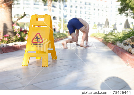 Man falling on tile near sign with inscription caution wet floor closeup Man falling on tile near sign with inscription caution wet floor closeup 78456444
