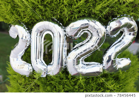 Number 2022 of silver helium balloons hanging on christmas tree closeup 78456445