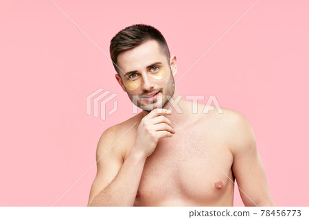 Portrait of smiling handsome man with golden eye patches on pink background Portrait of smiling handsome man with golden eye patches on pink background 78456773