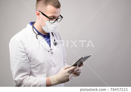 background for text, young male doctor in uniform looks at the phone, studio shot background for text, young male doctor in uniform looks at the phone, studio shot 78457221