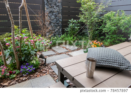 Coffee break on the wooden deck (veranda) in a small garden with a gabion 78457897