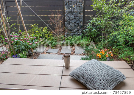 Coffee break on the wooden deck (veranda) in a small garden with a gabion 78457899