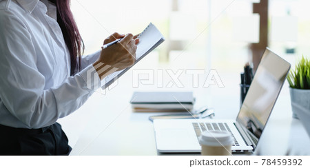 A joyful woman taking note concentrates on a webinar on her laptop computer. A joyful woman taking note concentrates on a webinar on her laptop computer. 78459392