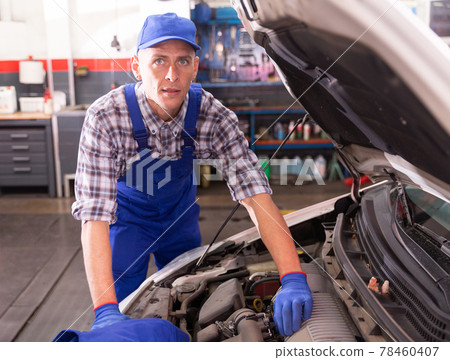 Car mechanic looking at open car hood for internal checking Car mechanic looking at open car hood for internal checking 78460407