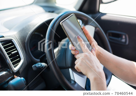 A faceless woman uses a mobile phone while driving a car. The girl uses the navigation in the smartphone 78460544