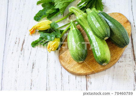 Fresh healthy uncooked green zucchini on a wooden kitchen table. Diet menu concept. Copy space. Fresh healthy uncooked green zucchini on a wooden kitchen table. Diet menu concept. Copy space. 78460789