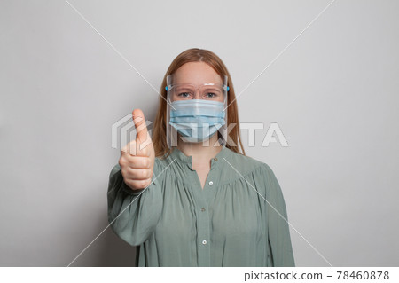 Woman in medical protective mask and face shields showing thumb up on white background Woman in medical protective mask and face shields showing thumb up on white background 78460878