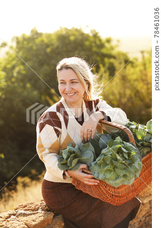 Woman with cabbage sitting on brick fence 78461036