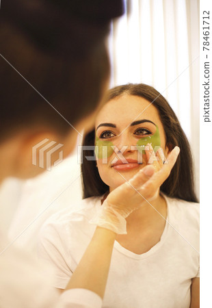 Cosmetician applying eye patches on face of woman 78461712