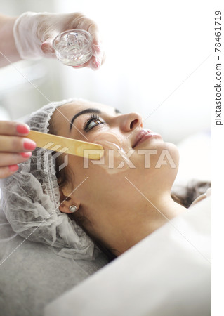 Crop beautician applying acid peeling in salon 78461719