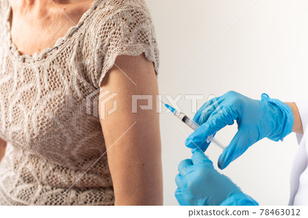 A doctor giving an injection of a covid-19 vaccine to an elderly patient. 78463012