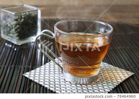 Oolong tea leaves and a cup of oolong tea in a glass cube container 78464960
