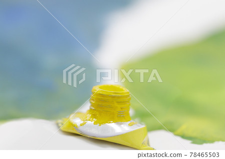 tube of watercolor yellow paint against the background of blue painted sheet 78465503