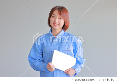 一個穿著制服的年輕女子，微笑著，左手拿著平板電腦 78471019