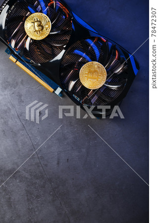 Gold Bitcoin on the video card cooler on a dark background top view. Gold Bitcoin on the video card cooler on a dark background top view. 78472307