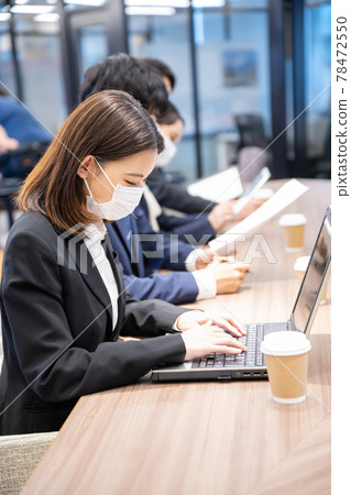 Young woman wearing a mask and working in a coworking space 78472550