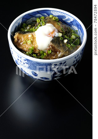 Photographed a teriyaki bowl of yellowtail topped with hot balls and plenty of small onions on a black background 78472894
