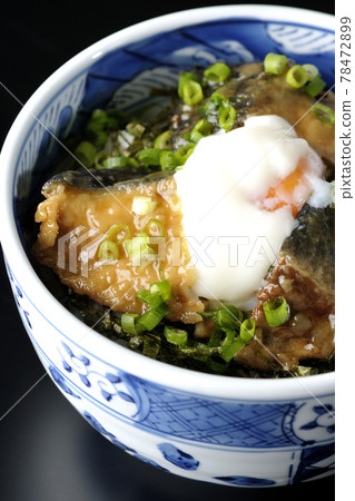 Photographed a teriyaki bowl of yellowtail topped with hot balls and plenty of small onions on a black background 78472899