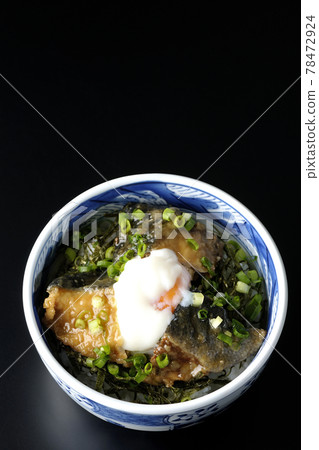 A bird's-eye view of a yellowtail teriyaki rice bowl topped with hot balls and plenty of small onions on a black background 78472924