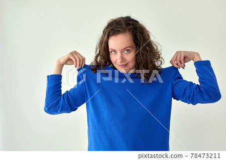 Smiling woman in blue knitted sweater white background Smiling woman in blue knitted sweater white background 78473211