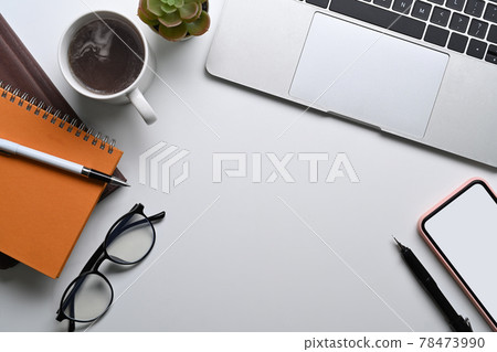 Top view white office desk with laptop computer, mobile pone, glasses, notebook and coffee cup. 78473990