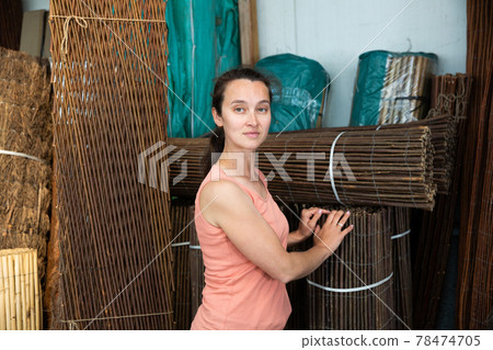 Young woman choosing organic wooden fence for gardening Young woman choosing organic wooden fence for gardening 78474705