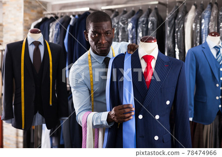 Afro-american man seller is showing jacket and tie in shop Afro-american man seller is showing jacket and tie in shop 78474966