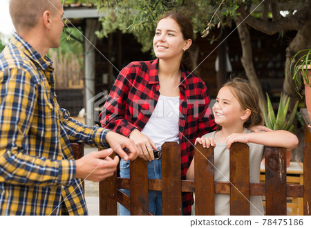 Man, woman and girl talking near fence 78475186