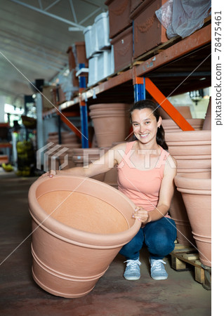Young woman customer choosing big clay pot for garden Young woman customer choosing big clay pot for garden 78475461