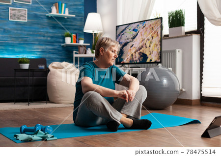 Senior woman sitting in lotus position on yoga mat training body muscles slimming weight 78475514