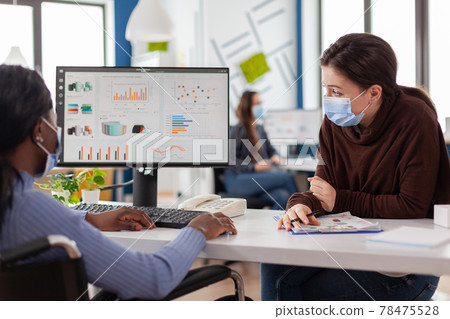 Immobilized african entrepreneur working with colleague in new normal office Immobilized african entrepreneur working with colleague in new normal office 78475528