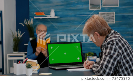 Senior woman looking at green screen monitor working from home Senior woman looking at green screen monitor working from home 78475570