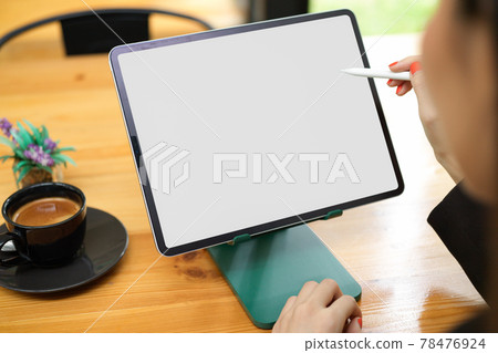 Close up view of female working on digital tablet with mock-up screen on the table in cafe 78476924
