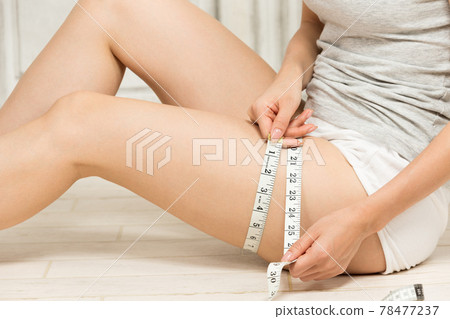 A woman who measures her thighs with a major. 78477237