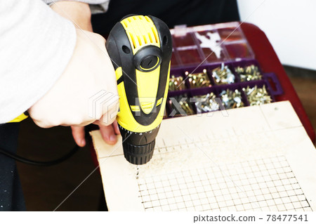 The man works as a drill in the workshop The man works as a drill in the workshop 78477541